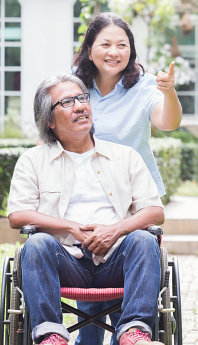 caregiver guiding a senior male on a wheelchair
